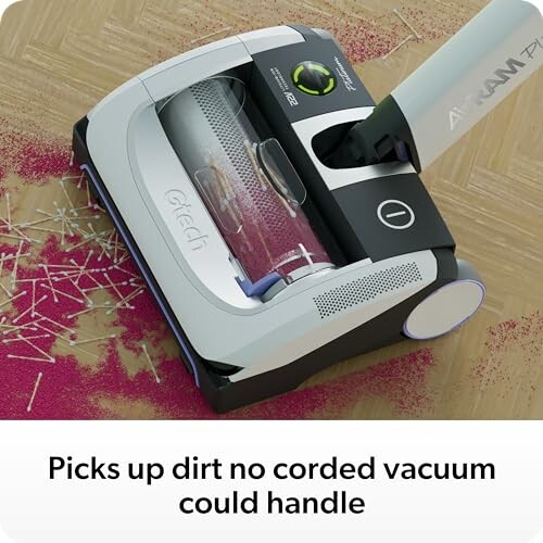 Cordless vacuum cleaner picking up dirt on a wooden floor.