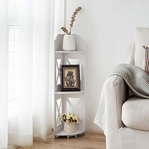 White corner shelf with decor items including a vase, framed picture, and flowers.