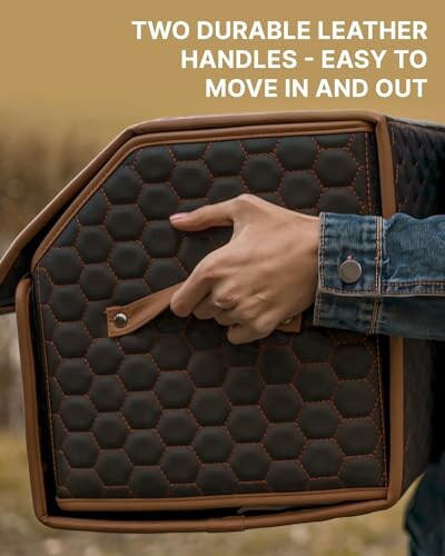 Hand holding a box with leather handles.