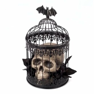 Gothic skull in a decorative cage with bat on top.