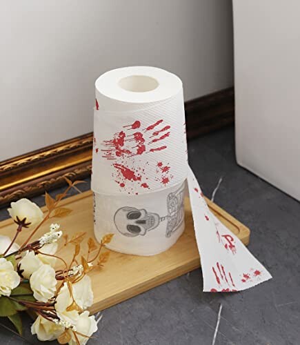 Toilet paper roll with red bloody handprints and skull design.