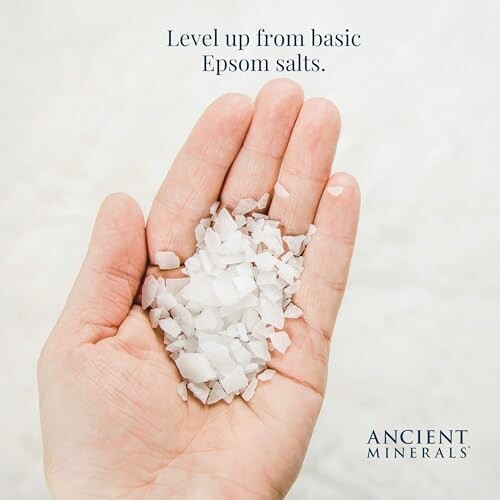 Hand holding coarse Epsom salts with text 'Level up from basic Epsom salts.'