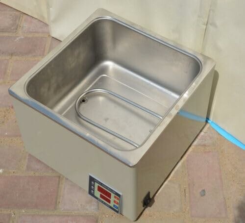 Stainless steel laboratory water bath on brick surface