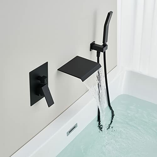 Modern black bath faucet with water flowing into a bathtub.