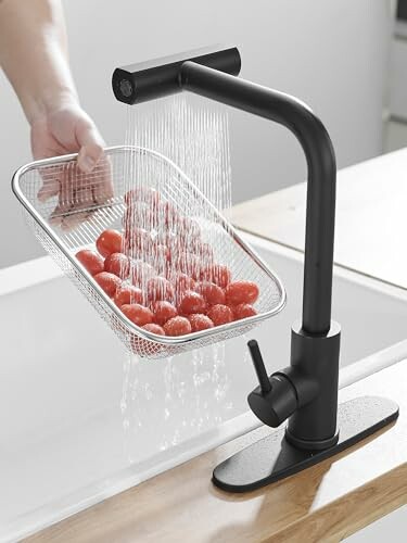 Hand washing cherry tomatoes under a modern faucet.