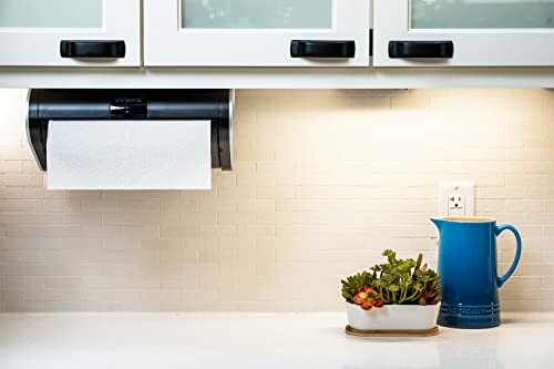 Under-cabinet paper towel holder with a blue pitcher and succulent planter