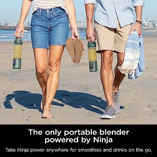 Two people walking on a beach holding portable blenders.