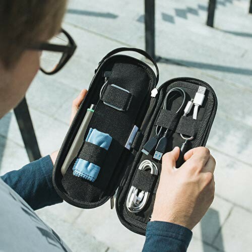 Person holding a tech accessory organizer with various cables and gadgets.