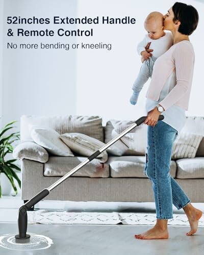 Woman holding a baby while using a mop with an extended handle.