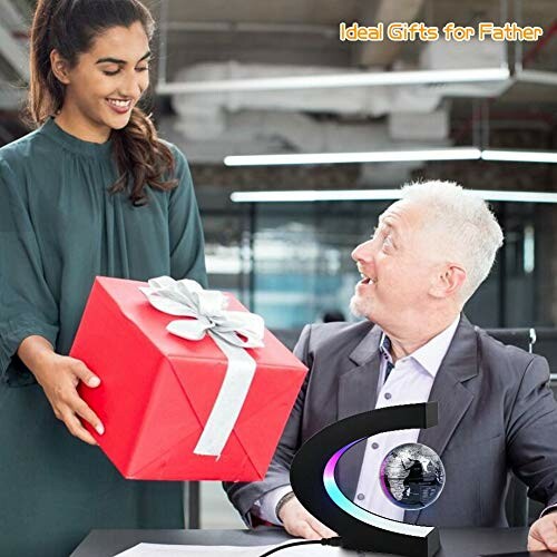 Woman giving a red gift box to a smiling man sitting at a desk.